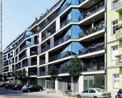 Skulpturaler Bau: Große, teils schräg gestellte Glasfassaden reflektieren im Berliner Samariterviertel Himmel und Nachbarschaft in verschiedenen Farben.