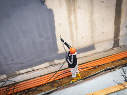 Ein Bauarbeiter dichtet eine Betonwand ab.